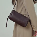 A dynamic showcase of the Cuirae genuine leather crossbody bag, highlighting its spacious interior, built-in pockets, and metal hardware details, as well as how the models demonstrate its versatility with various outfits.