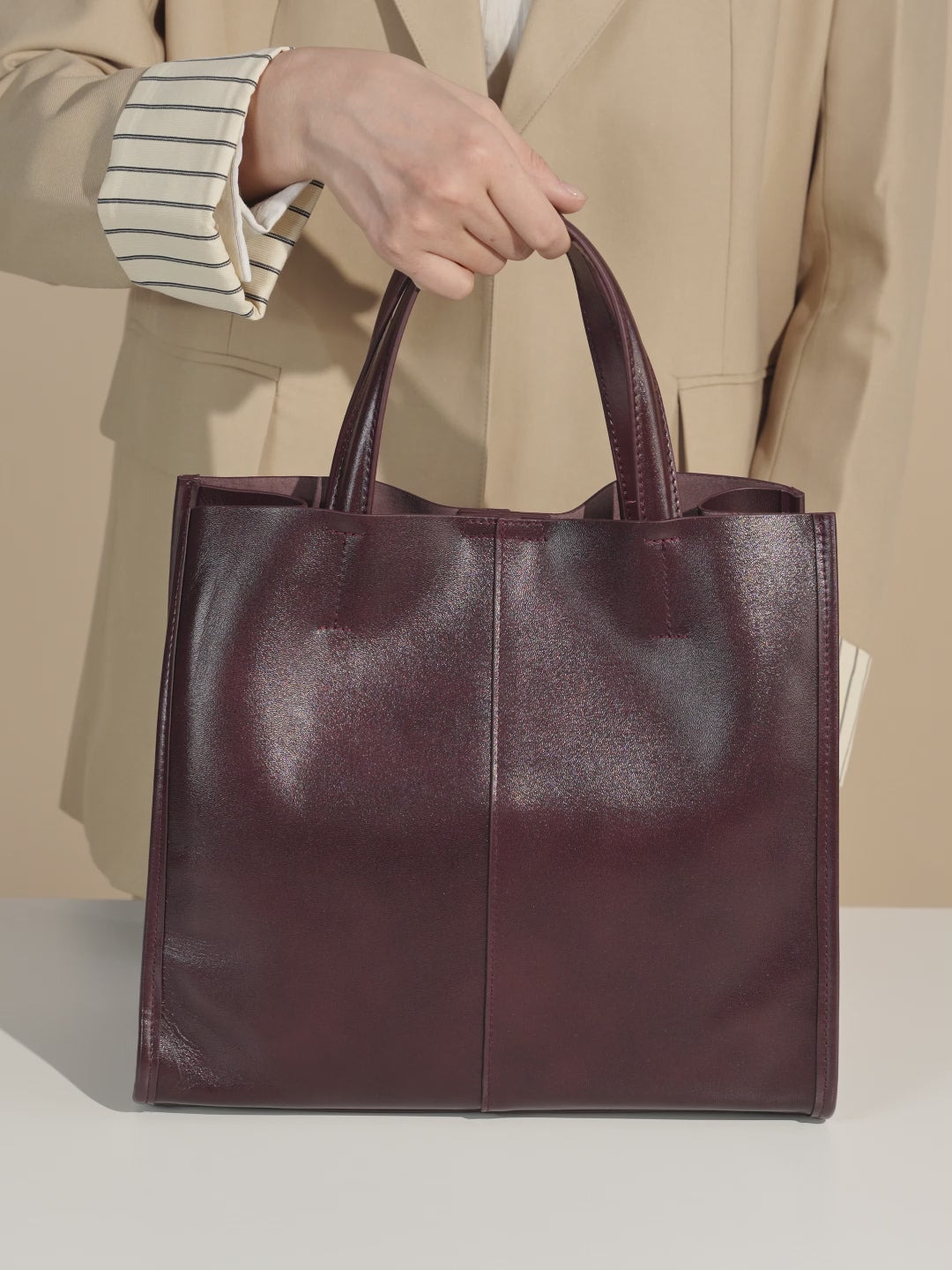 A dynamic showcase of the Cuirae genuine leather tote bag, highlighting its spacious interior, built-in pockets, and metal hardware details, as well as how the models demonstrate its versatility with various outfits.