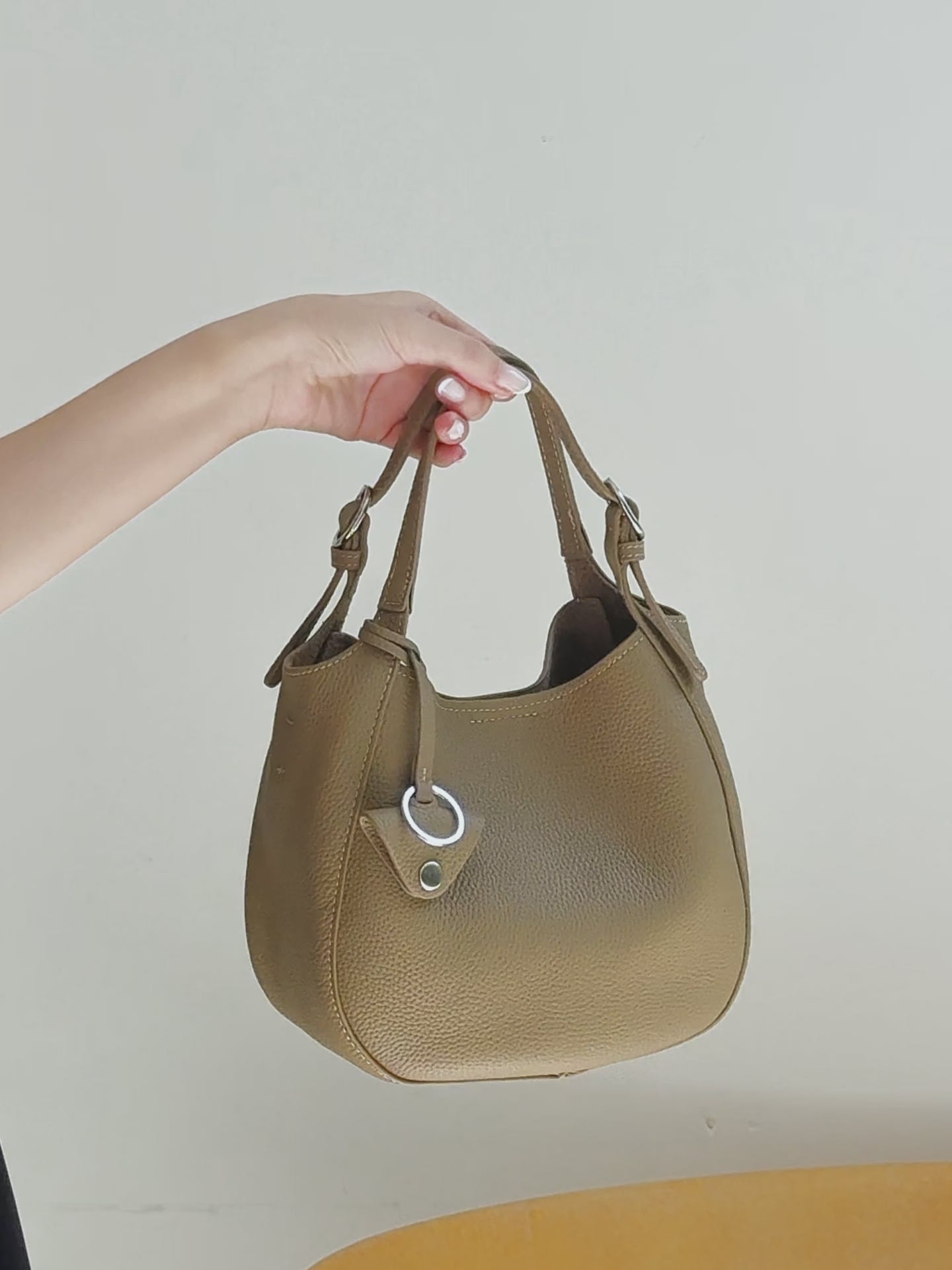 A dynamic showcase of the Cuirae genuine leather bucket bag, highlighting its spacious interior, built-in pockets, and metal craftsmanship details, as well as how the models demonstrate its versatility with various outfits.