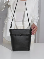 A dynamic showcase of the Cuirae genuine leather bucket bag, highlighting its spacious interior, built-in pockets, and metal hardware details, as well as how the models demonstrate its versatility with various outfits.