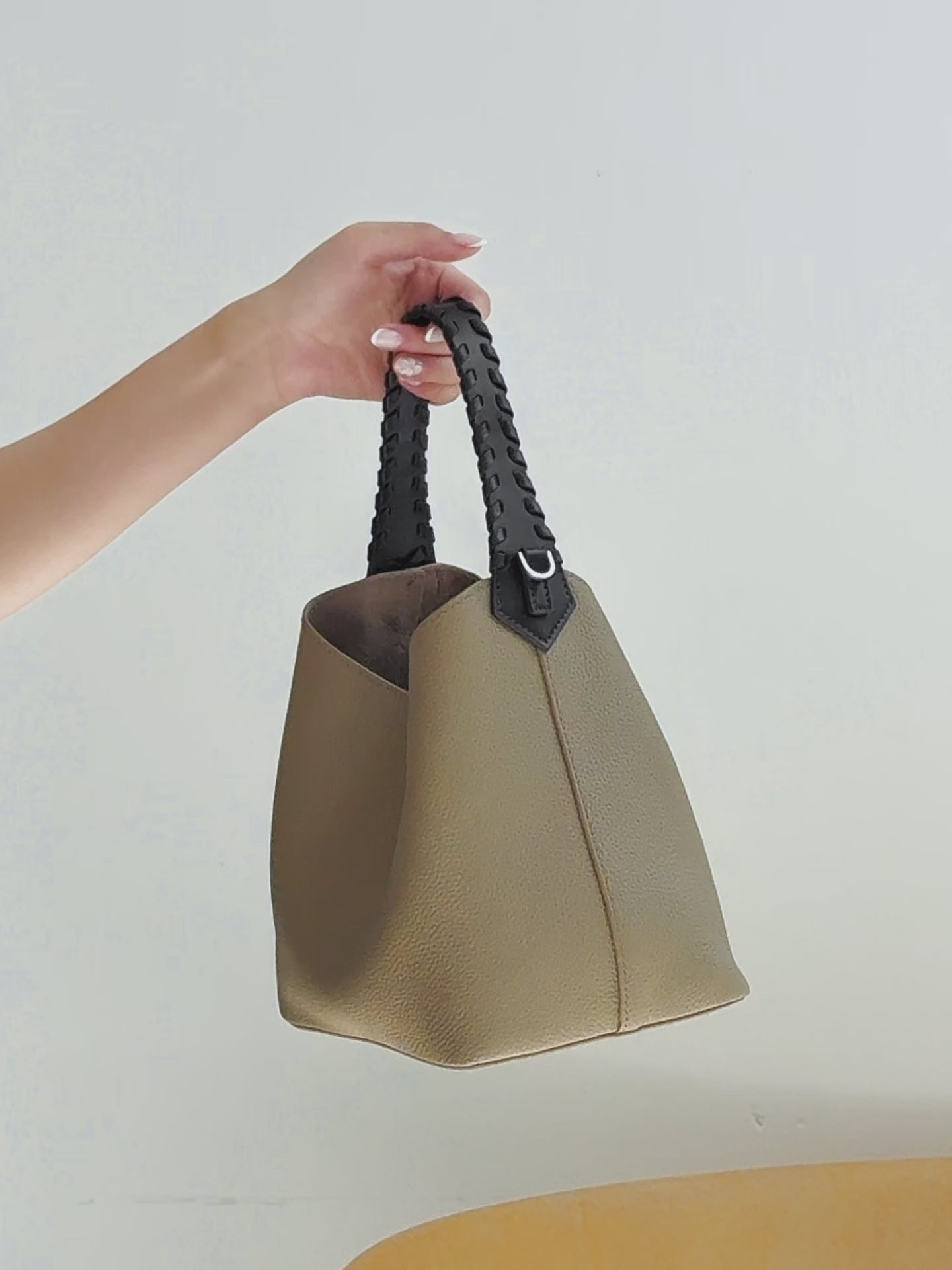 A dynamic showcase of the Cuirae genuine leather bucket bag， highlighting its spacious interior, built-in pockets, and craftsmanship details, while also demonstrating how models use different outfits to showcase the bag’s versatility.