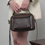A dynamic showcase of the Cuirae genuine leather shoulder bag, highlighting its spacious interior, built-in pockets, and metal hardware details, as well as how the models demonstrate its versatility with various outfits.